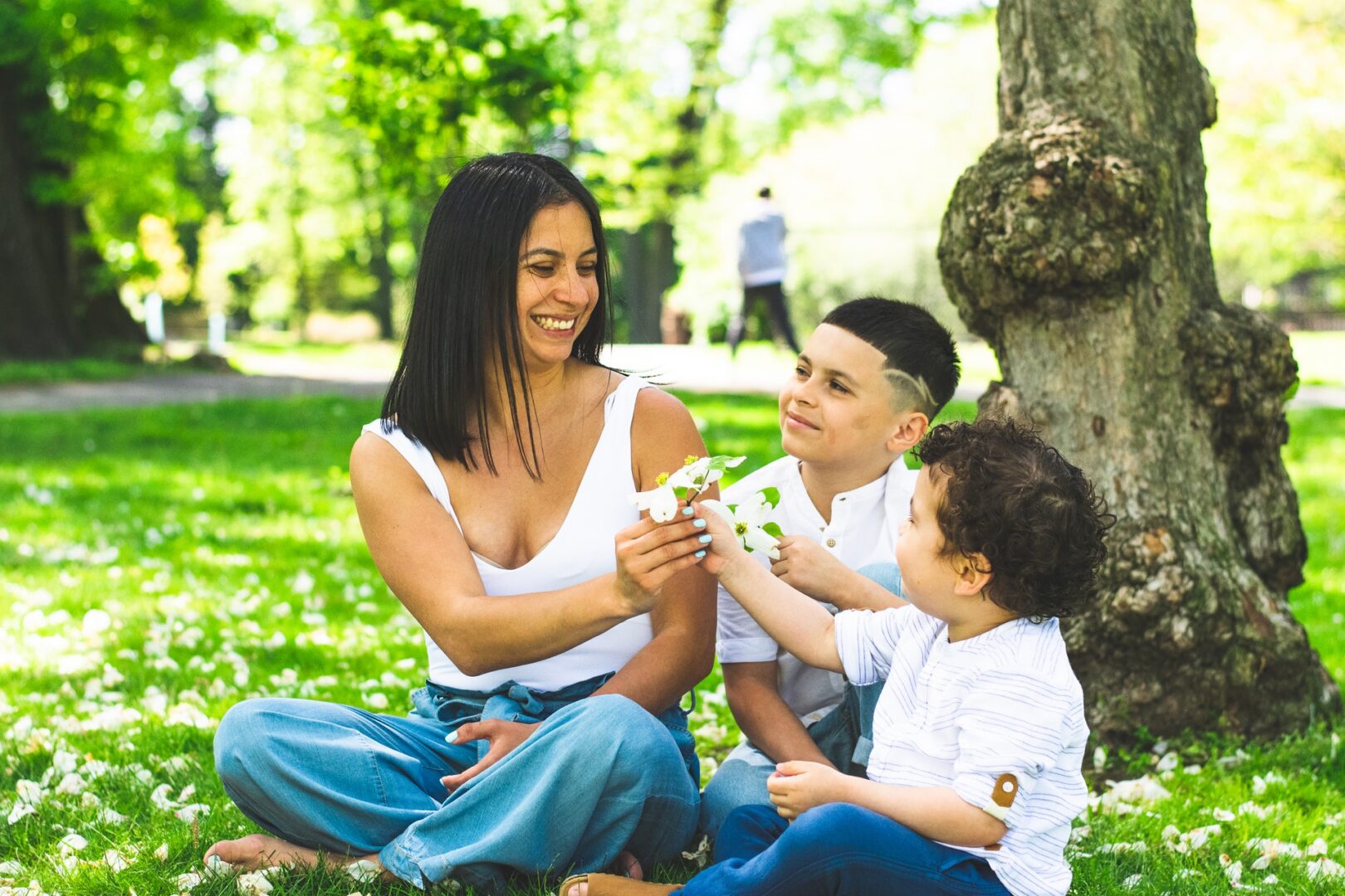 A woman and two children sitting on the grass.